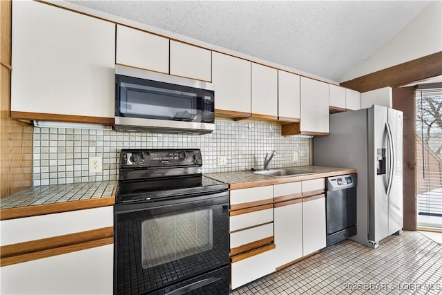 kitchen featuring a textured ceiling, vaulted ceiling, sink, black appliances, and white cabinets