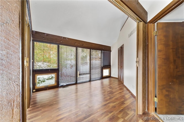 unfurnished room featuring lofted ceiling with beams and wood-type flooring