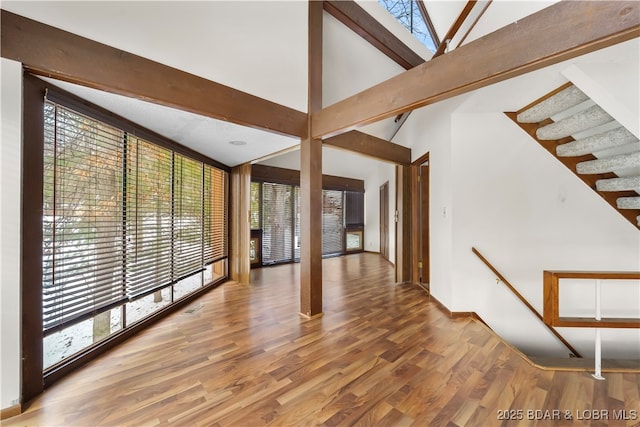 unfurnished room featuring hardwood / wood-style floors, high vaulted ceiling, and beamed ceiling