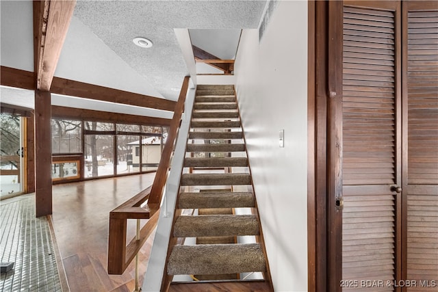 staircase featuring lofted ceiling with beams and a textured ceiling