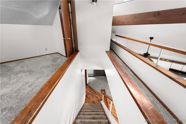 staircase featuring carpet flooring, ceiling fan, a textured ceiling, and lofted ceiling