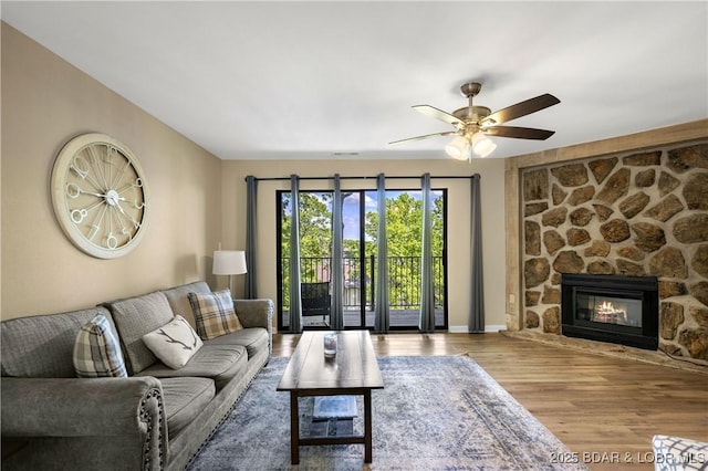 living room with a fireplace, wood-type flooring, and ceiling fan