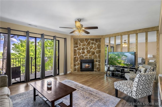 living room with ceiling fan, a fireplace, and wood-type flooring