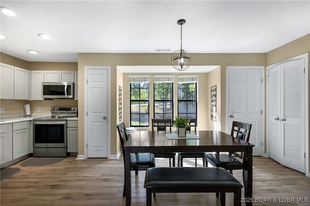 dining space with light wood-type flooring and an inviting chandelier