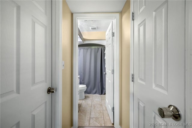 hall with light tile patterned floors and a textured ceiling