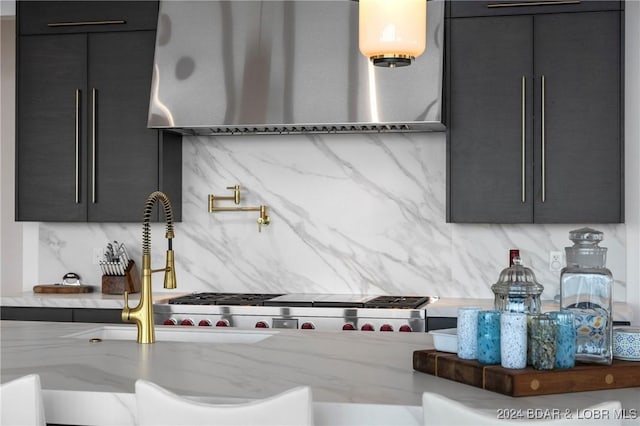 kitchen featuring decorative backsplash, light stone counters, and wall chimney exhaust hood