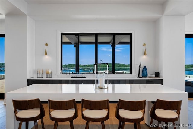 kitchen with a breakfast bar, a water view, and hanging light fixtures