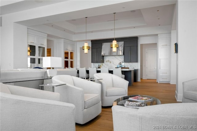 living room with light wood-type flooring and a tray ceiling