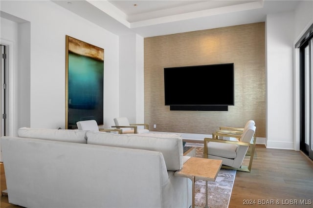 living room with a raised ceiling and wood-type flooring