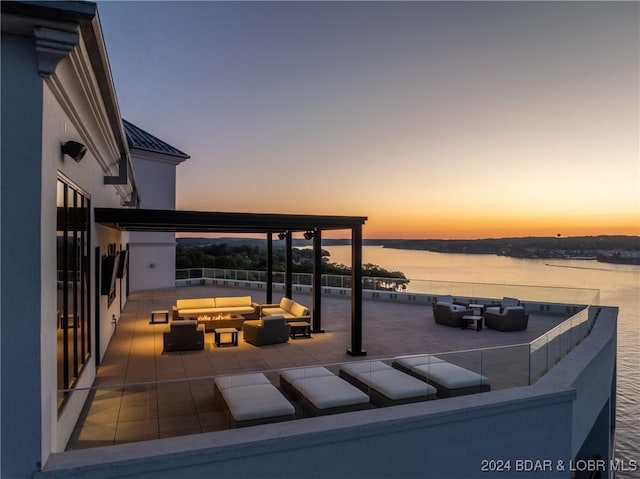 patio terrace at dusk with outdoor lounge area and a water view