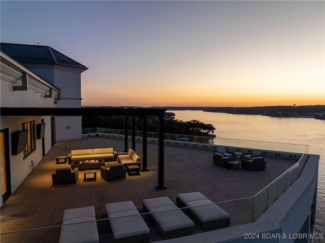 patio terrace at dusk with an outdoor hangout area and a water view