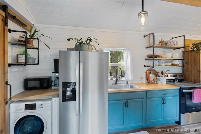 kitchen featuring wood walls, blue cabinets, sink, stainless steel appliances, and washer / clothes dryer