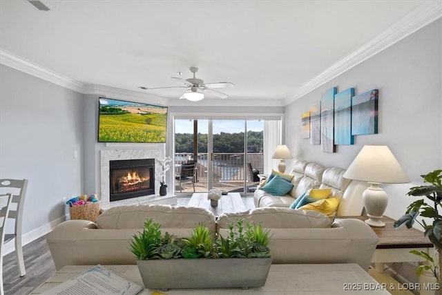 living room with hardwood / wood-style flooring, ceiling fan, a premium fireplace, and crown molding