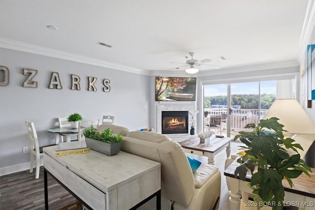 living room with a high end fireplace, dark hardwood / wood-style floors, ceiling fan, and crown molding