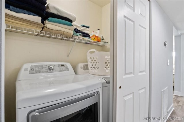 washroom with washer and clothes dryer and light wood-type flooring