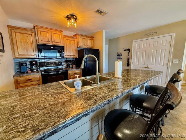 2500 Bay Point Ln Unit 234, Osage Beach, MO 65065 - kitchen featuring visible vents, a sink, a kitchen breakfast bar, backsplash, and black appliances