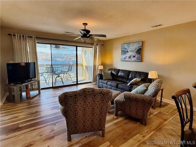 living room featuring ceiling fan, a textured ceiling, and hardwood / wood-style flooring