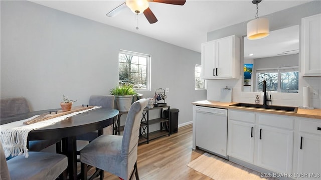 kitchen with dishwasher, decorative light fixtures, white cabinets, and sink