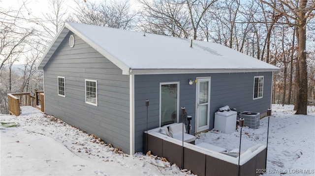 snow covered house featuring central AC