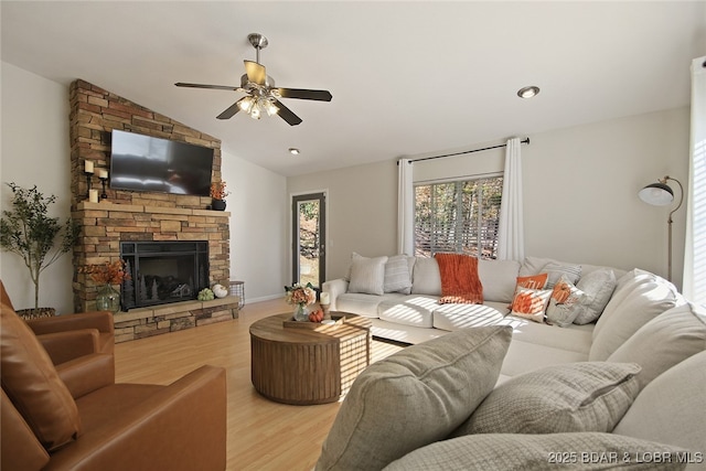 living room with a fireplace, light hardwood / wood-style flooring, lofted ceiling, and ceiling fan