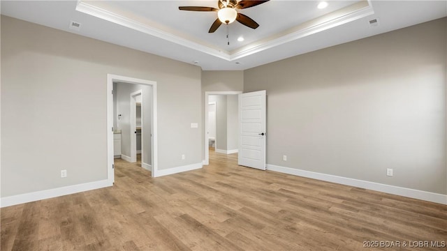 unfurnished bedroom with a tray ceiling, ceiling fan, and light hardwood / wood-style floors