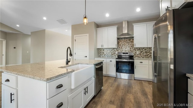 kitchen featuring appliances with stainless steel finishes, pendant lighting, wall chimney exhaust hood, white cabinets, and sink