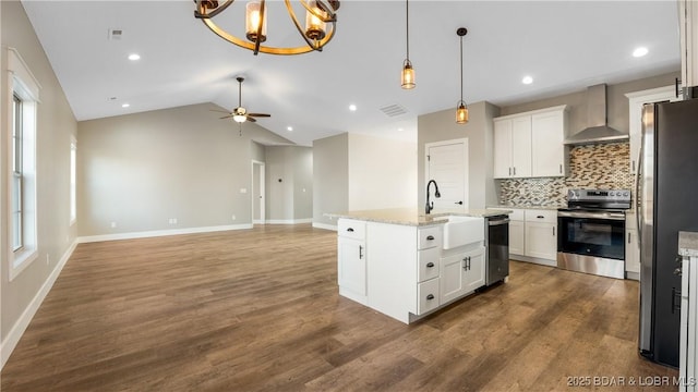 kitchen featuring wall chimney exhaust hood, stainless steel appliances, vaulted ceiling, a kitchen island with sink, and white cabinets