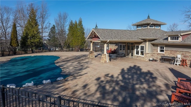 rear view of property featuring a patio area and a covered pool