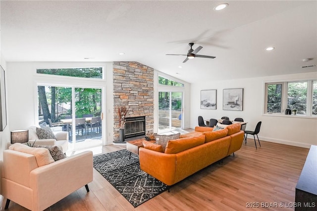 living room featuring lofted ceiling, a stone fireplace, and hardwood / wood-style floors