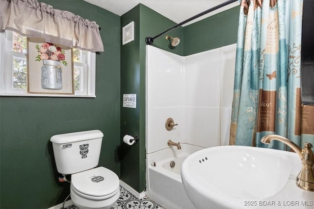 full bathroom featuring toilet, a textured ceiling, shower / tub combo with curtain, and sink