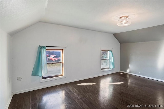 additional living space with lofted ceiling, a textured ceiling, and dark wood-type flooring