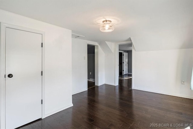 unfurnished room featuring lofted ceiling and dark wood-type flooring