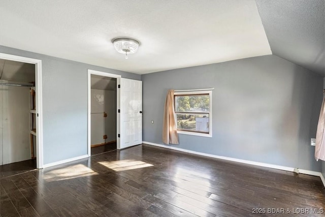 unfurnished bedroom featuring lofted ceiling, dark wood-type flooring, a textured ceiling, and a closet