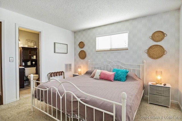 carpeted bedroom with a textured ceiling and connected bathroom