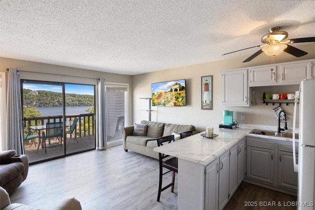 kitchen featuring gray cabinets, a breakfast bar area, kitchen peninsula, white refrigerator, and sink