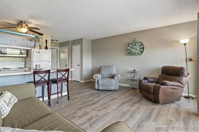 living room with a textured ceiling, ceiling fan, and light hardwood / wood-style floors