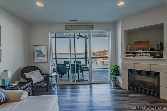 interior space featuring a water view, dark wood-type flooring, a tile fireplace, and plenty of natural light