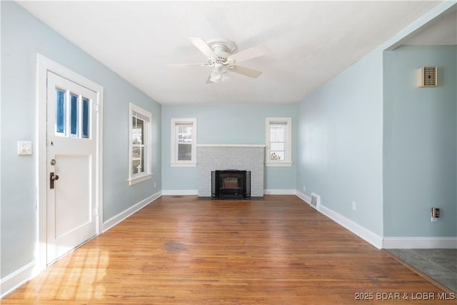 unfurnished living room featuring ceiling fan, a brick fireplace, and wood-type flooring