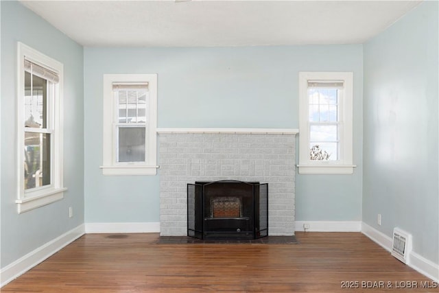 unfurnished living room featuring a healthy amount of sunlight, hardwood / wood-style floors, and a fireplace