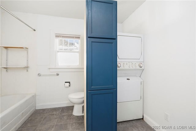 bathroom with stacked washer and dryer, tile walls, and toilet