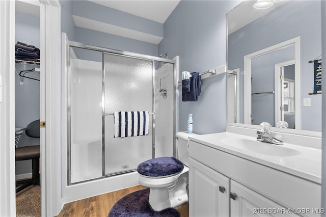 bathroom featuring vanity, wood-type flooring, walk in shower, and toilet