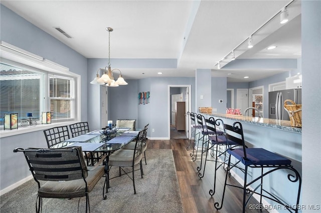 dining area featuring a notable chandelier, dark wood-type flooring, and rail lighting