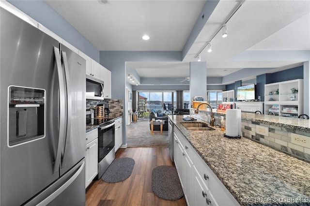 kitchen with dark hardwood / wood-style floors, stainless steel appliances, white cabinets, dark stone counters, and sink