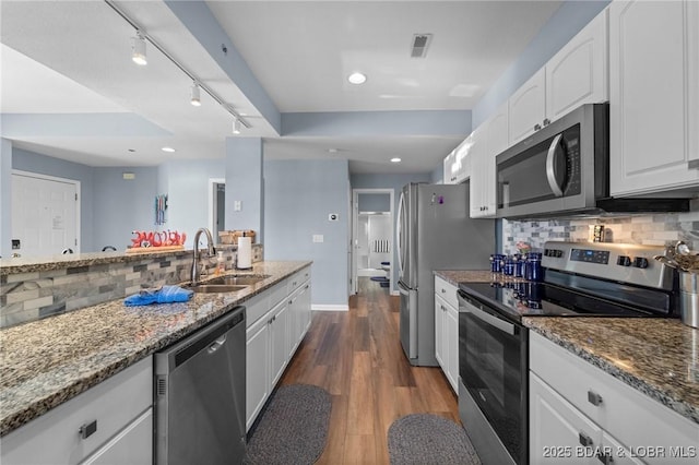 kitchen with stainless steel appliances, white cabinetry, and stone countertops