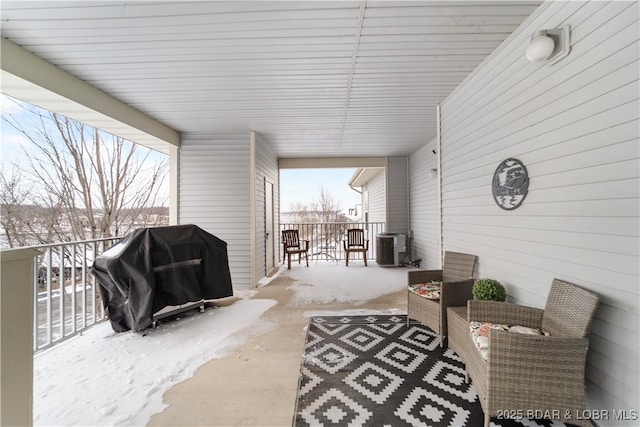 snow covered patio with central air condition unit and a grill