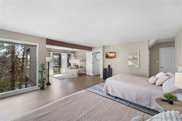 bedroom with beamed ceiling, a textured ceiling, french doors, and wood-type flooring