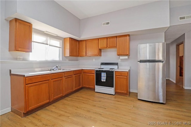 kitchen with sink, white electric range, stainless steel refrigerator, and light wood-type flooring