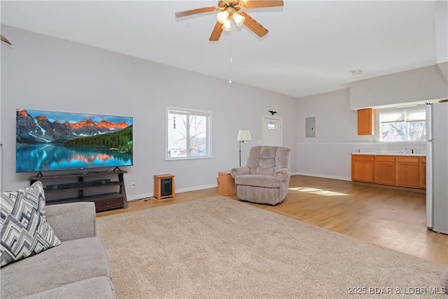 living room with ceiling fan, electric panel, light hardwood / wood-style flooring, and a wealth of natural light