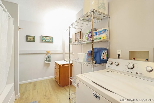 clothes washing area with sink, washer / dryer, and light hardwood / wood-style floors