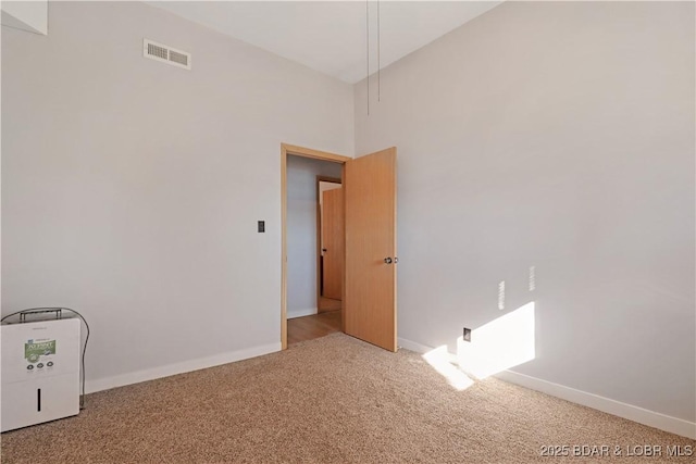 carpeted spare room with a towering ceiling